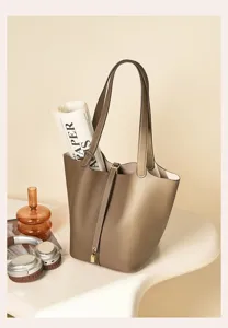 Premium leather bucket bag detail, elegant taupe color, fine stitching, metal lock closure.