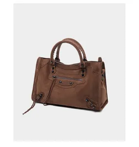 Brown suede motorcycle shoulder bag closeup showcasing metal studs, tassels and front zip pocket.
