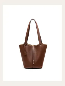 Close-up detail of brown genuine leather bucket bag showing fine stitching and lock hardware.