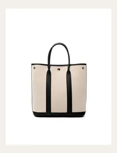Canvas tote bag detail view, black leather trim and handles, structured vertical design.