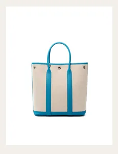 Vertical canvas tote bag with blue leather trim, stylish shoulder handbag for women.