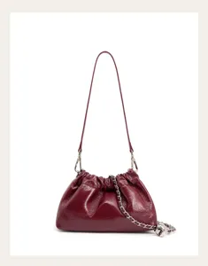 Dettaglio borsa a tracolla in pelle bordeaux con catena argento e teschio decorativo.