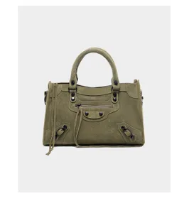 Olive green suede motorcycle handbag featuring metal rivets, long tassels, and front zip pocket.