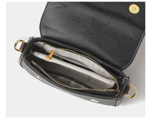 Detailed view of black genuine leather crossbody bag interior with zipper compartments and gold hardware.