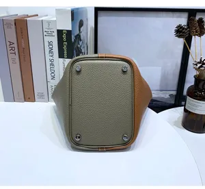 Genuine leather bucket bag bottom view with metal feet, two-tone stylish handbag for women.