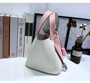 Two-tone leather bucket bag detail view, featuring pink and white pebbled leather and lock.