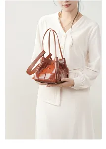 Close-up detail of brown woven leather handbag held by model, showcasing premium texture.