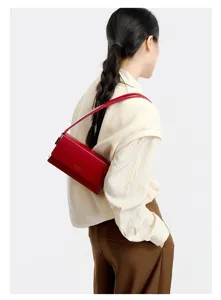 Red leather underarm shoulder bag detail showing minimalist flap design and fine strap.