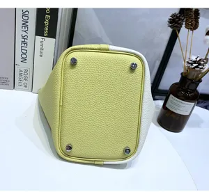 Genuine leather bucket bag bottom detail showing metal feet, stylish color block design.