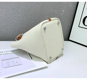 Premium cowhide leather bucket handbag for women, elegant white tote bag with metal feet details.