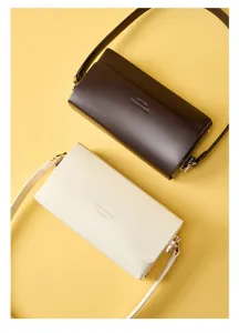 Minimalist leather shoulder bag detail, elegant design with chain strap and flap closure.