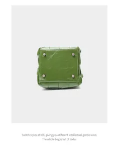 Detailed view of green woven leather handbag bottom, genuine cowhide craftsmanship.