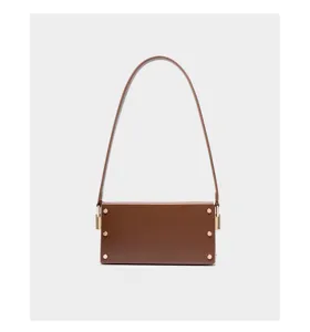 Detailed view of the brown leather shoulder bag, highlighting metal hardware and clean stitching.