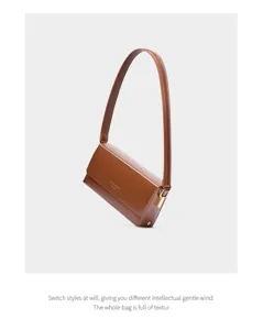 Brown leather underarm shoulder bag detail, elegant minimalist baguette handbag close up.