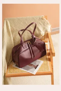 Burgundy leather boston bag detail showing premium texture, zipper closure and soft knit chair.