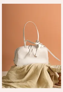 Detailed view of white genuine leather bowling shoulder bag, commuter minimalist style.