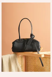 Detailed shot of black leather Boston shoulder bag, premium commuting handbag with dual top handles.