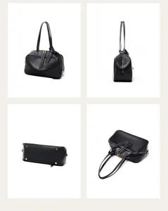 Detail view of black leather Boston bag, showing dual handles, metal bottom feet and structure.
