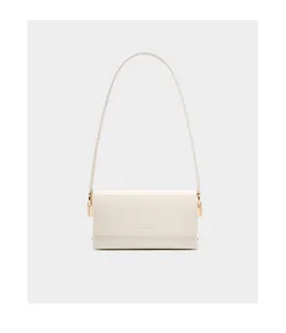 Detail view of minimalist white leather shoulder bag with sleek gold hardware and strap.