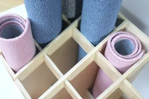 Wooden Montessori carpet rack organizer with rolled work rugs for classroom and early education.