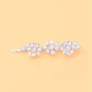 Vista detallada de la horquilla con flor de cristal brillante y perla, accesorio elegante.
