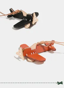 Detailed view of handcrafted vegetable-tanned leather airplane keychain and bag pendant.