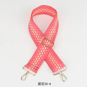Gedetailleerde opname van roze jacquard tassenriem met verstelbaar goudkleurig beslag.
