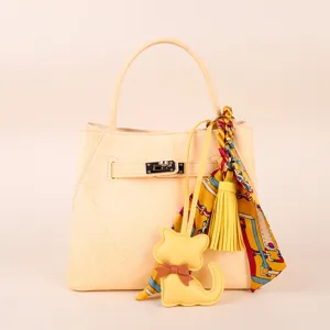Detail view of the elegant yellow leather handbag featuring a chic silk scarf and cute cat charm.