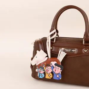 Detailed view of brown PU leather handbag featuring cute pony and cartoon pendant charm.