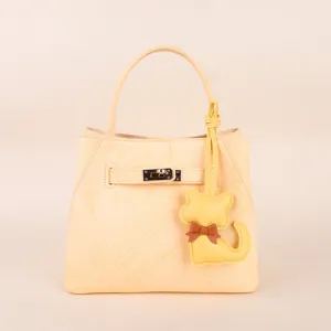 Cute yellow leather handbag with metal turn lock and kitten charm for women daily fashion style.