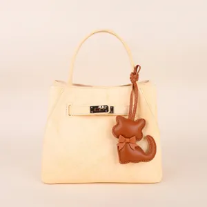 Light yellow leather handbag with cute cat pendant and metal lock, elegant daily women bag.