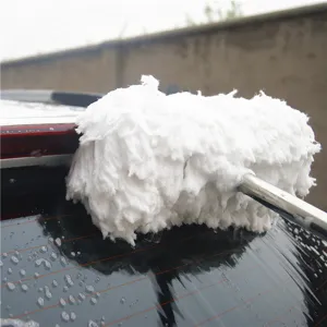 Detail shot of car wash mop with soft milk silk bristles cleaning car window with foam suds.