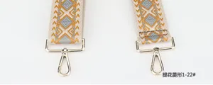 Detailed view of wide embroidered bag strap with geometric diamond pattern and gold hardware.