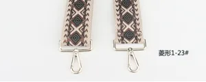 Detailed view of wide woven bag strap with geometric diamond pattern and gold metal hooks.
