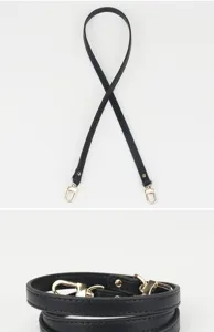 Détail de sangle de sac de rechange en cuir noir, bandoulière fine avec des fermoirs métalliques.