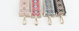 Detail shot of colorful geometric embroidered wide bag straps with gold metal hooks.