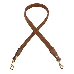 Close-up detail of the brown leather replacement bag strap, featuring durable golden metal clasps.