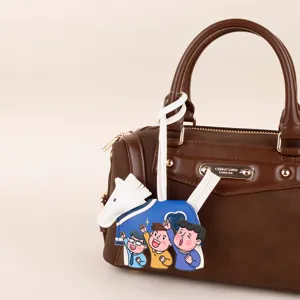 Detailed view of a cute cartoon pony bag charm hanging on a stylish brown leather handbag.