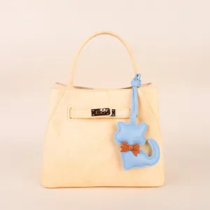 Close-up detail shot of the elegant yellow leather handbag featuring a cute blue cat charm.