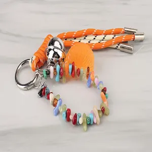Close-up detail of the colorful woven keychain featuring irregular stone beads, bell and resin charm.