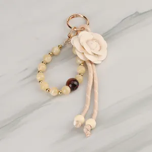 Elegant camellia flower beaded keychain with woven lanyard and metal ring for bag accessory.