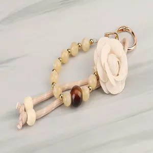 Detailed shot of braided beaded lanyard with elegant fabric camellia flower and gold hardware.