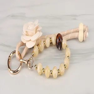 Beaded keychain detail featuring fabric flower and golden metal ring accessory close up.