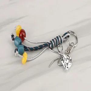 Colorful braided keychain charm with beads and metal pendant for bags or keys detail.