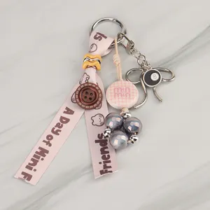 Detailed view of a cute pink ribbon keychain charm with beads and metal 8-ball pendant.