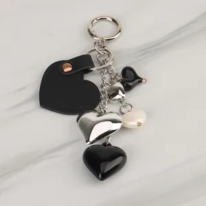 Close-up detail of chic black and silver heart keyring charm with leather and metal pendants.
