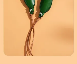 Detail view of handmade green leather tulip leaf pendant with brown cord and white stitching.