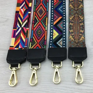 Woven wide bag strap with leather ends and gold clasps, colorful ethnic geometric pattern.