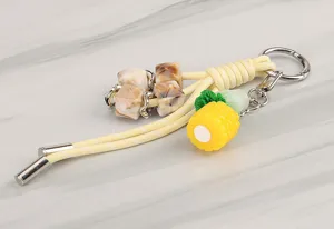Detailed view of the braided keychain with marbled beads and cute corn pendant, metal hardware.