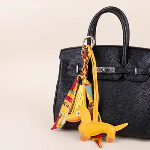 Detailed view of the cute yellow dachshund bag charm with colorful silk scarf and tassels.